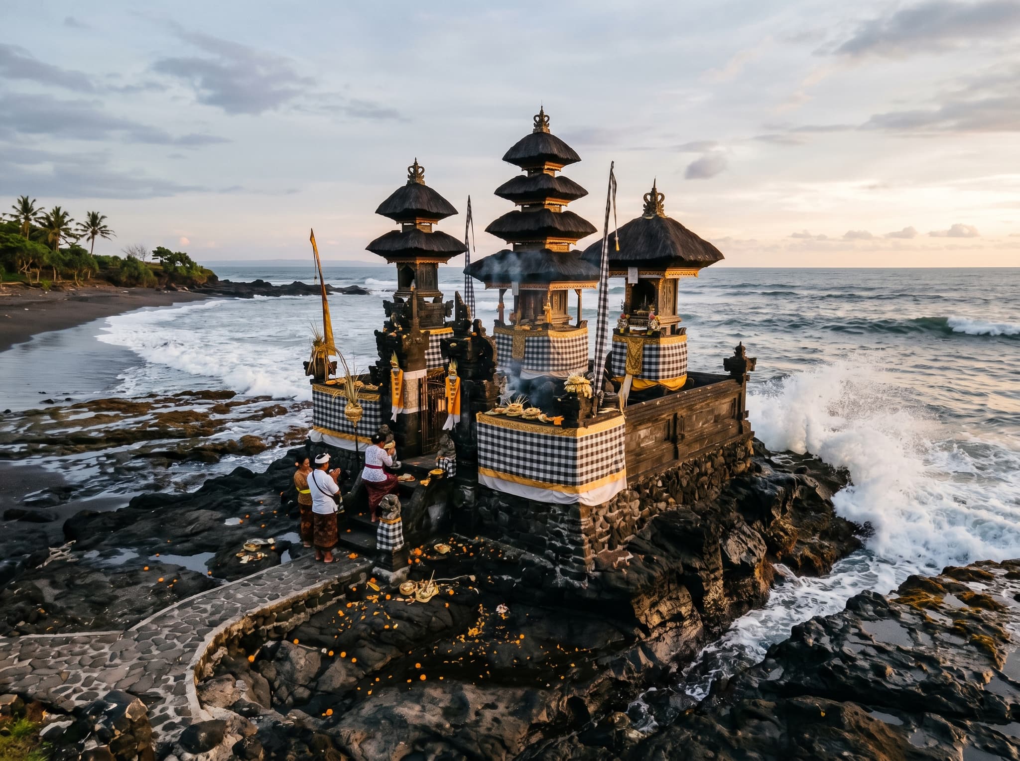 Pura Batulumbang sea temple at the southern end of Seseh Beach, perched on dark volcanic rock at the water's edge — the small, active temple that anchors the beach's southern end and gives the location its ceremonial character