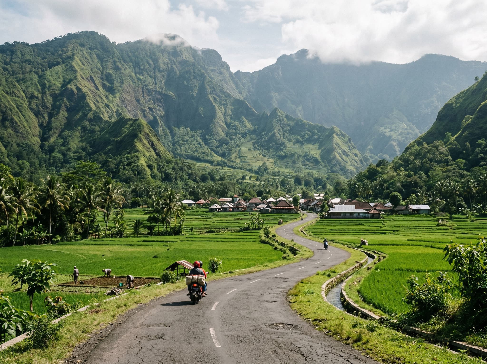 The winding paved road through the Sembalun Valley approaching Sembalun Lawang village, flanked by rice fields and framed by the green volcanic ridges of East Lombok — illustrating the scenic drive to Selong Hill described in the Getting There section.