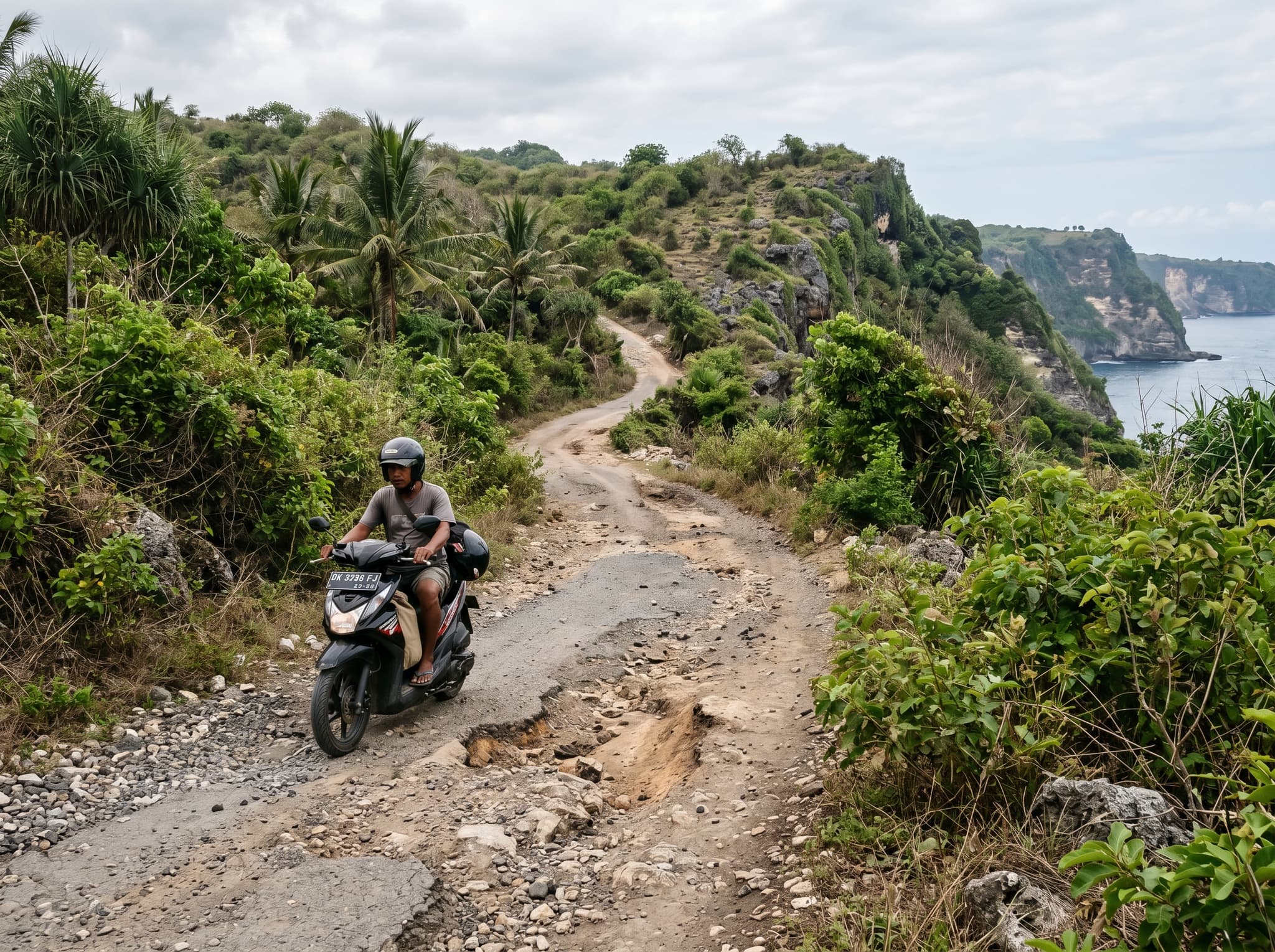 The rough coastal road on Nusa Penida leading toward the western coast, showing the narrow, partially unpaved conditions described in the article's transport section — context for the recommendation to hire a private driver rather than ride a scooter