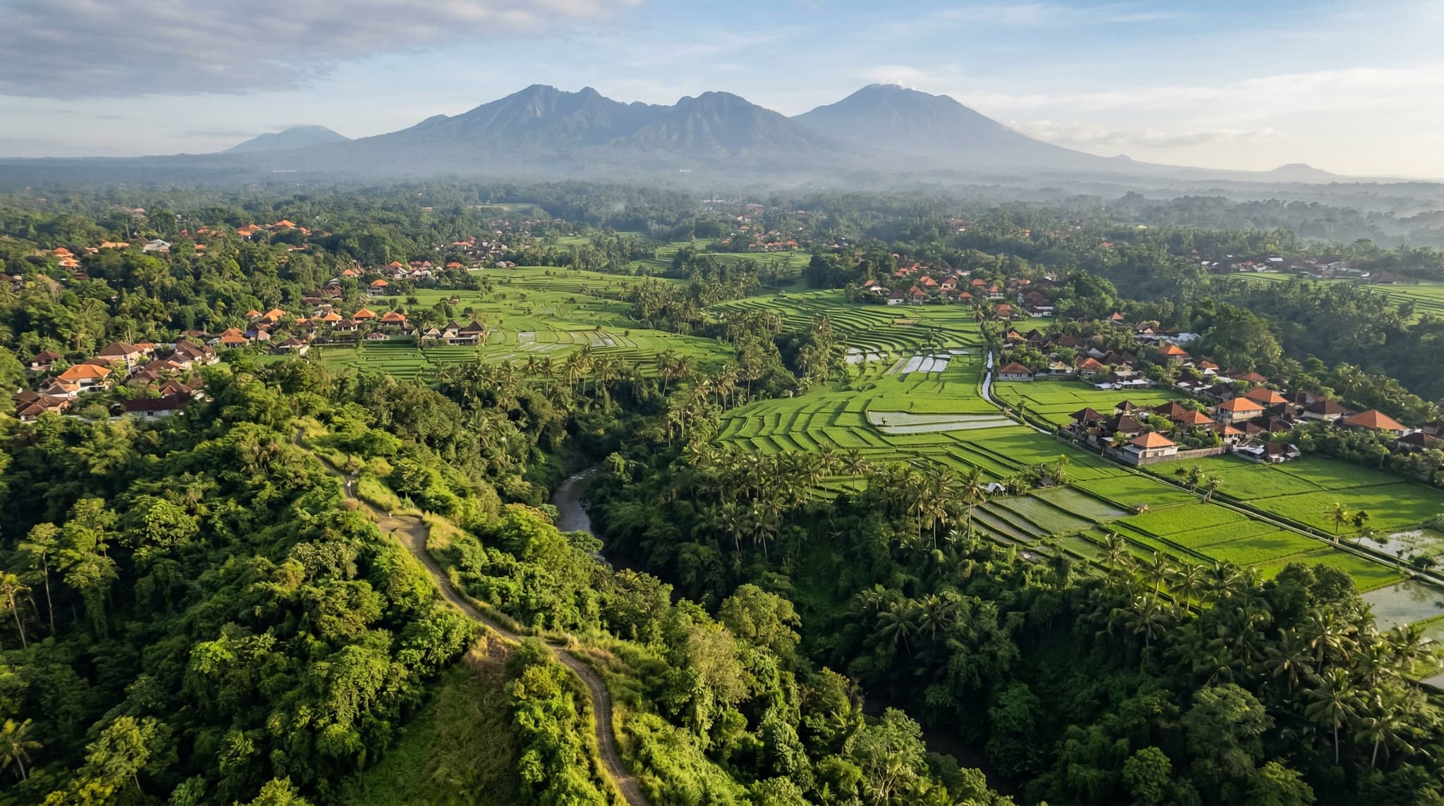 Aerial or elevated view of Ubud's patchwork of rice paddies, village rooftops, and jungle canopy in central Bali — establishing the article's core argument that Ubud is a collection of distinct villages, not a single town