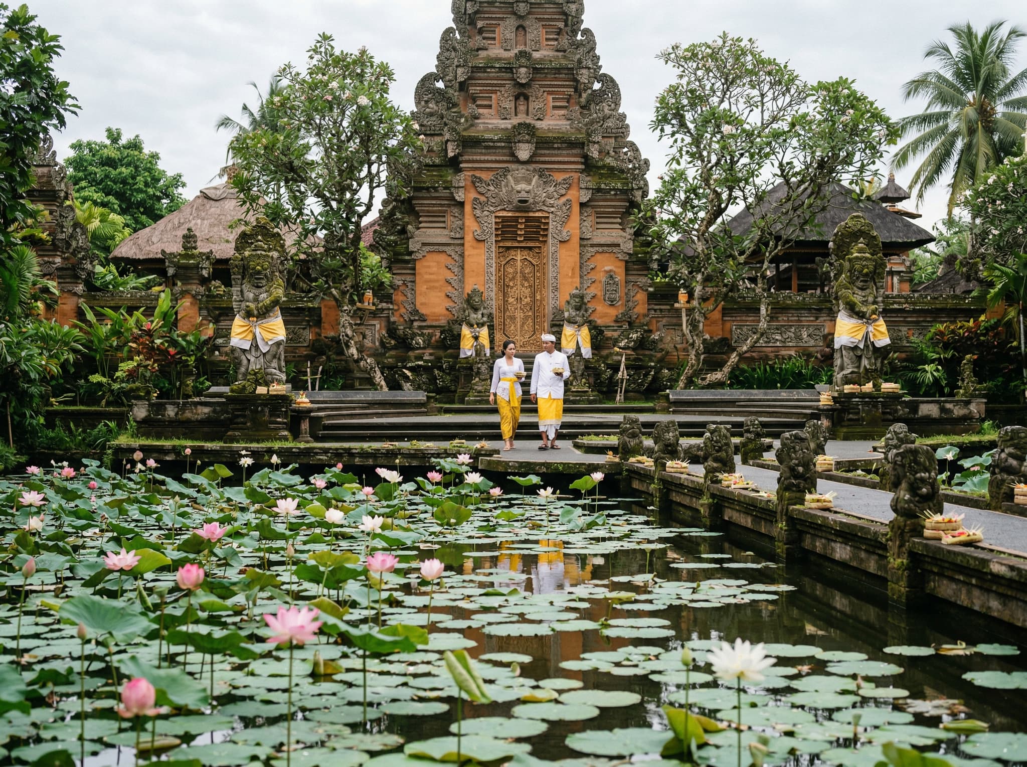Saraswati Temple lotus pond in early morning light, Ubud — pink lotus blooms covering the water's surface in front of carved stone temple gates, illustrating the article's tip to visit before the tour buses arrive