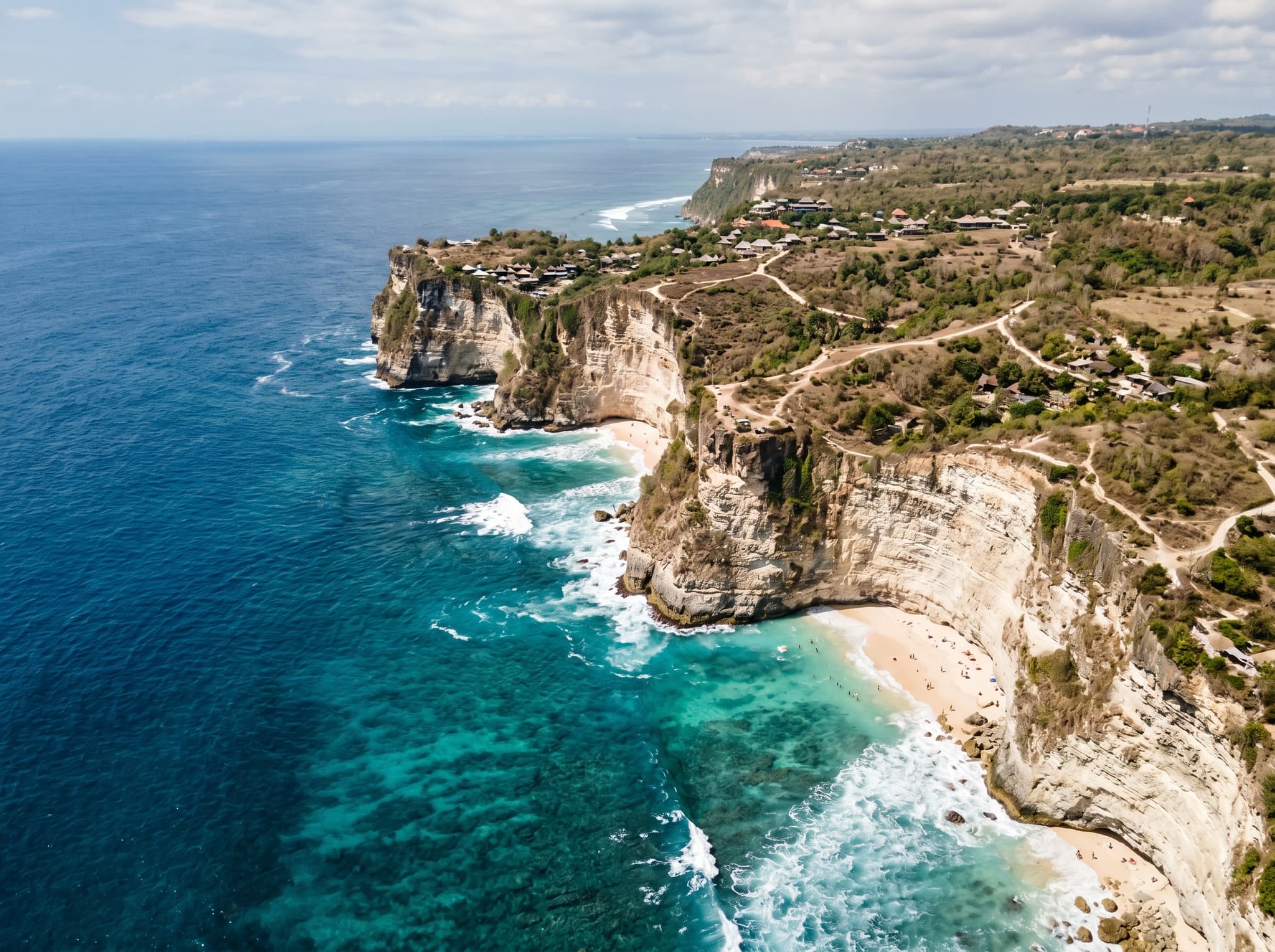 The limestone cliff coastline of Bali's Bukit Peninsula viewed from the water or a high vantage point — dramatic vertical cliffs meeting turquoise sea, establishing the geological character that makes Gunung Payung and its neighbors distinct from other Bali beaches