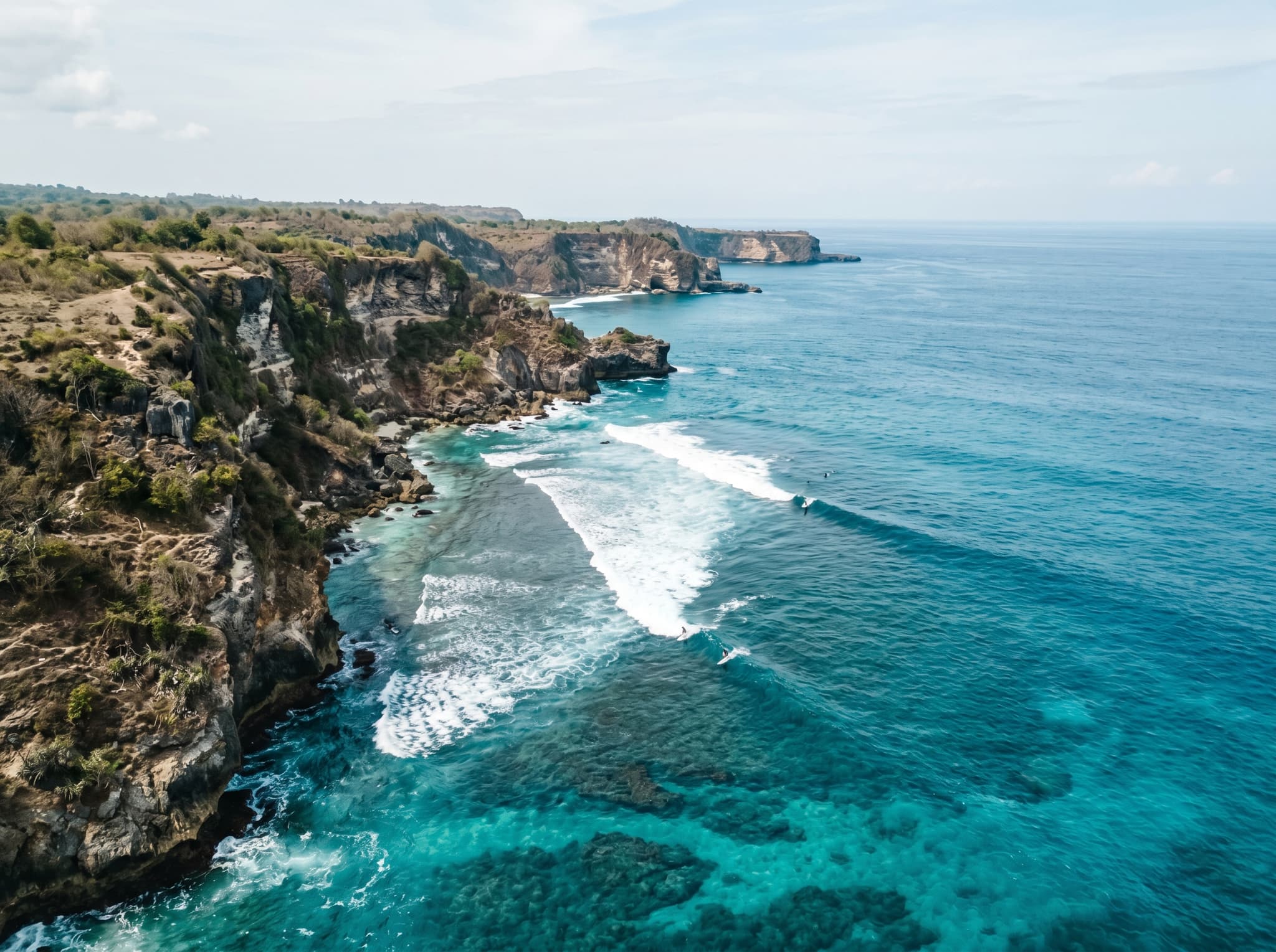 A wide view of the Nusa Islands coastline from the water, showing the uncrowded, remote character of Nusa Ceningan's southwestern shore — reinforcing the article's closing argument about wave quality over crowd density