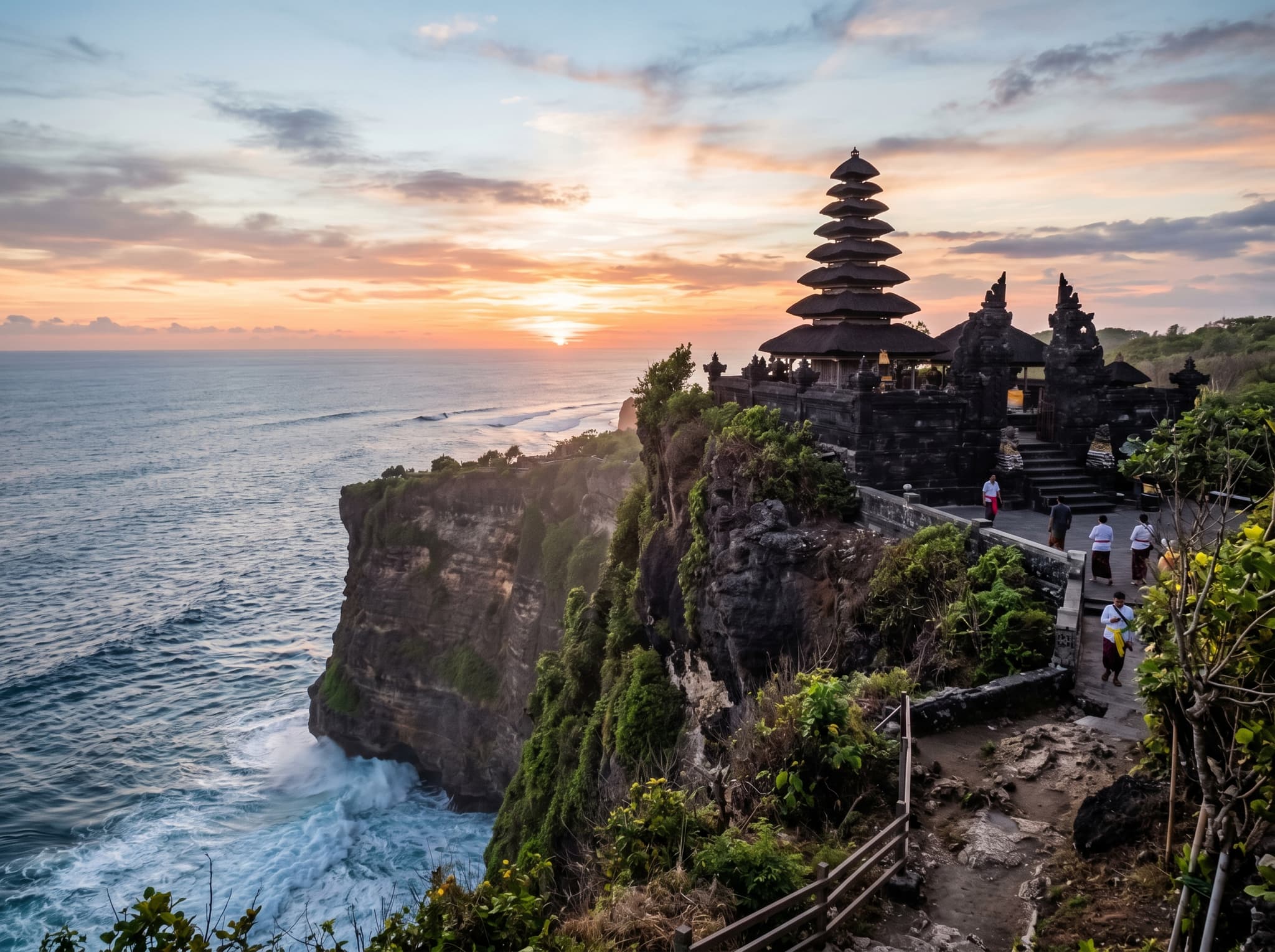 Uluwatu Temple perched on its clifftop above the Indian Ocean at sunset, with the Kecak fire dance performance visible or implied — supporting the article's itinerary suggestion to combine a morning at Melasti Beach with an afternoon Kecak performance at Uluwatu Temple.