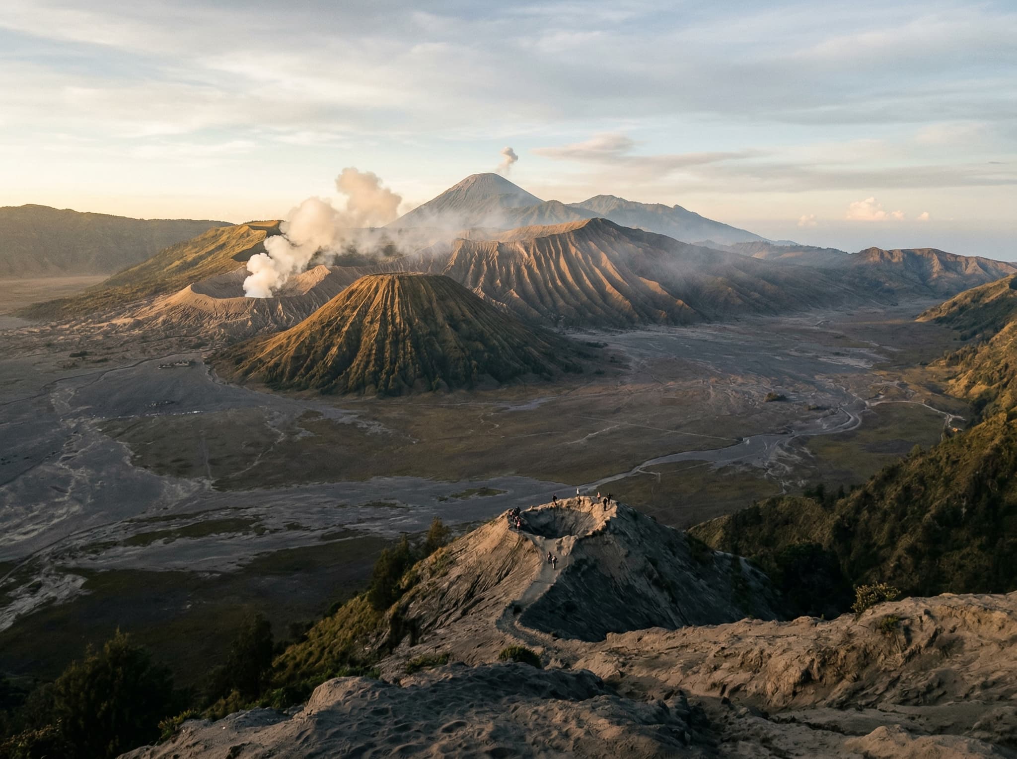 Mount Bromo's active crater and the Sea of Sand caldera viewed from the Cemoro Lawang rim at sunrise — the volcanic landscape that draws travelers to stay at Cafe Lava Hostel, just 300 meters from the park entrance