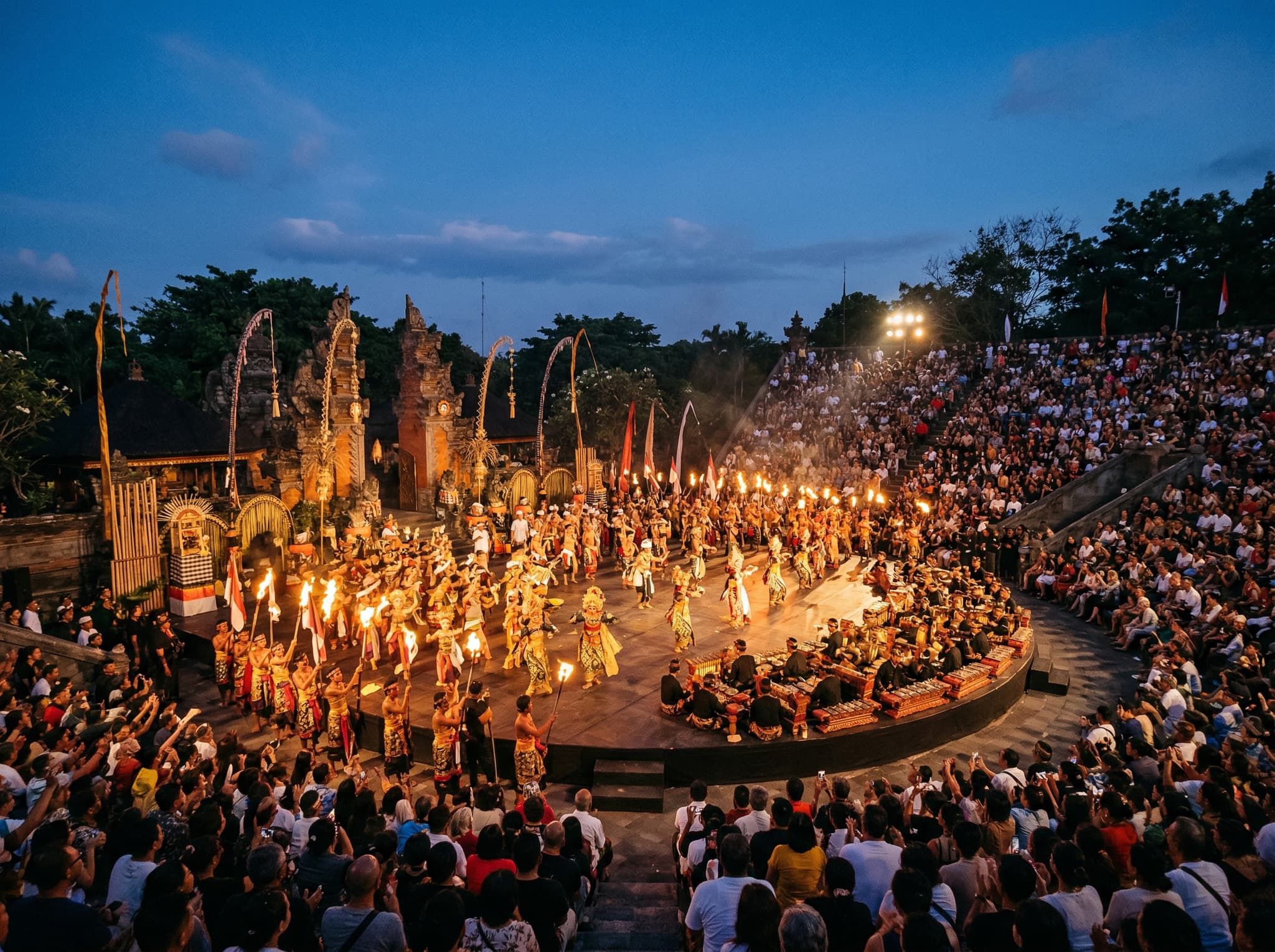 A large-scale opening ceremony at the Bali Arts Festival at Ardha Candra Amphitheater, with hundreds of performers in traditional dress filling the stage — conveying the extraordinary scale and communal energy of Bali's most important annual cultural event