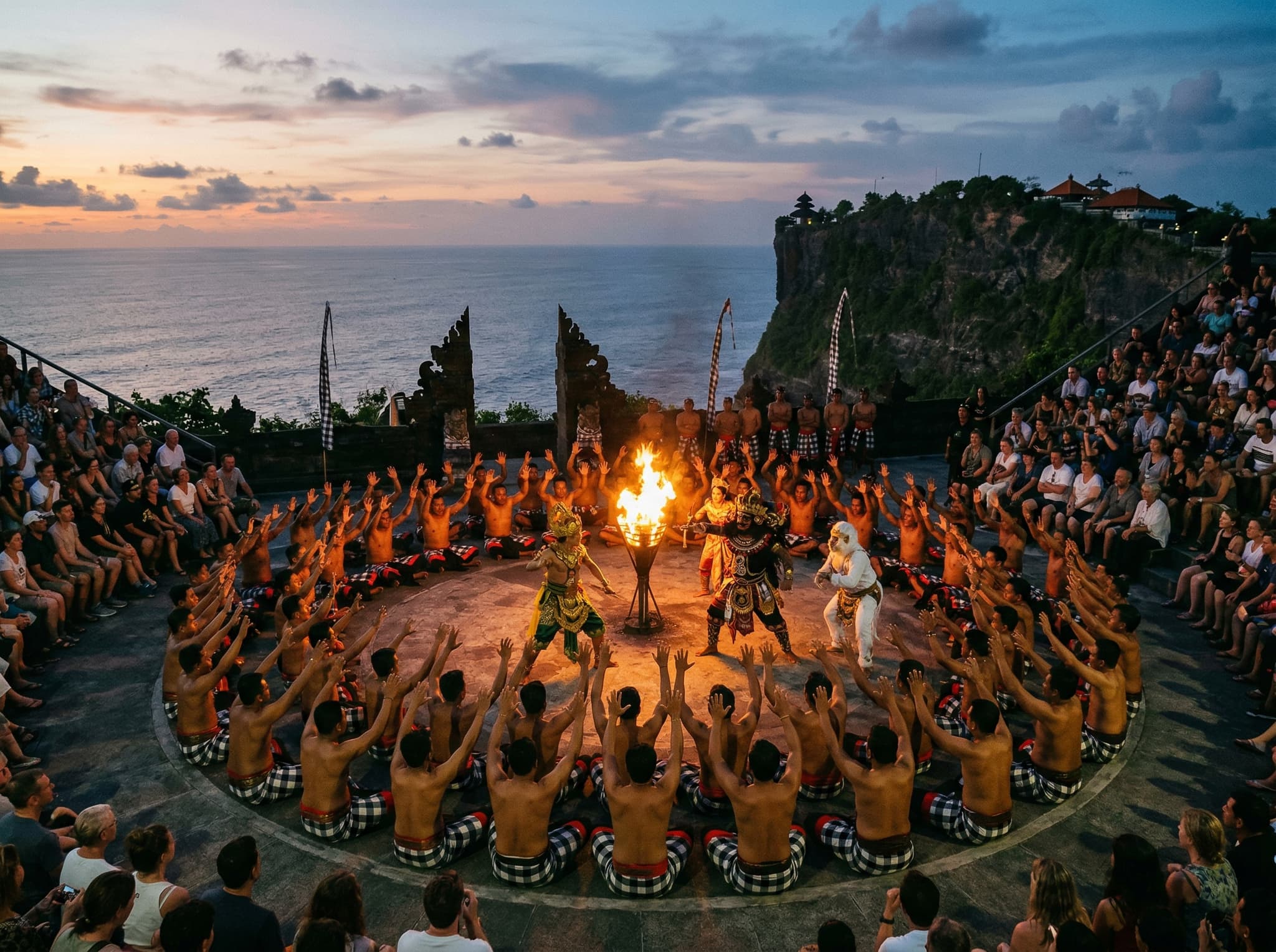 The Kecak fire dance performance at Uluwatu's clifftop stone amphitheater at dusk — a circle of bare-chested men chanting around a central fire with the darkening Indian Ocean and last light of sunset visible behind them, illustrating the article's central cultural experience