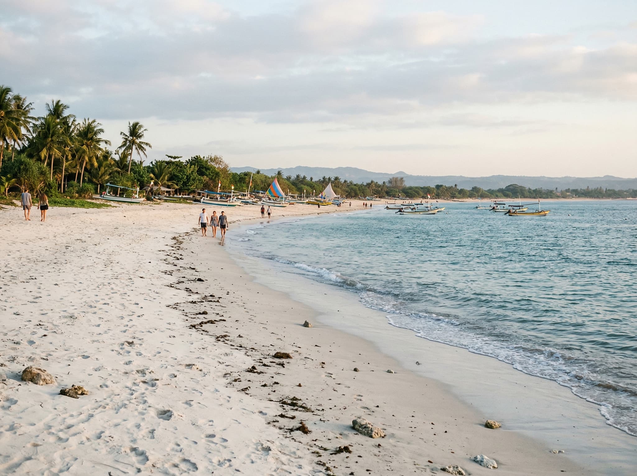 The quieter southern stretch of Kedonganan Beach in afternoon light, with clean pale sand, calm water, and sparse visitors — showing the contrast with the busier pier area described in the article