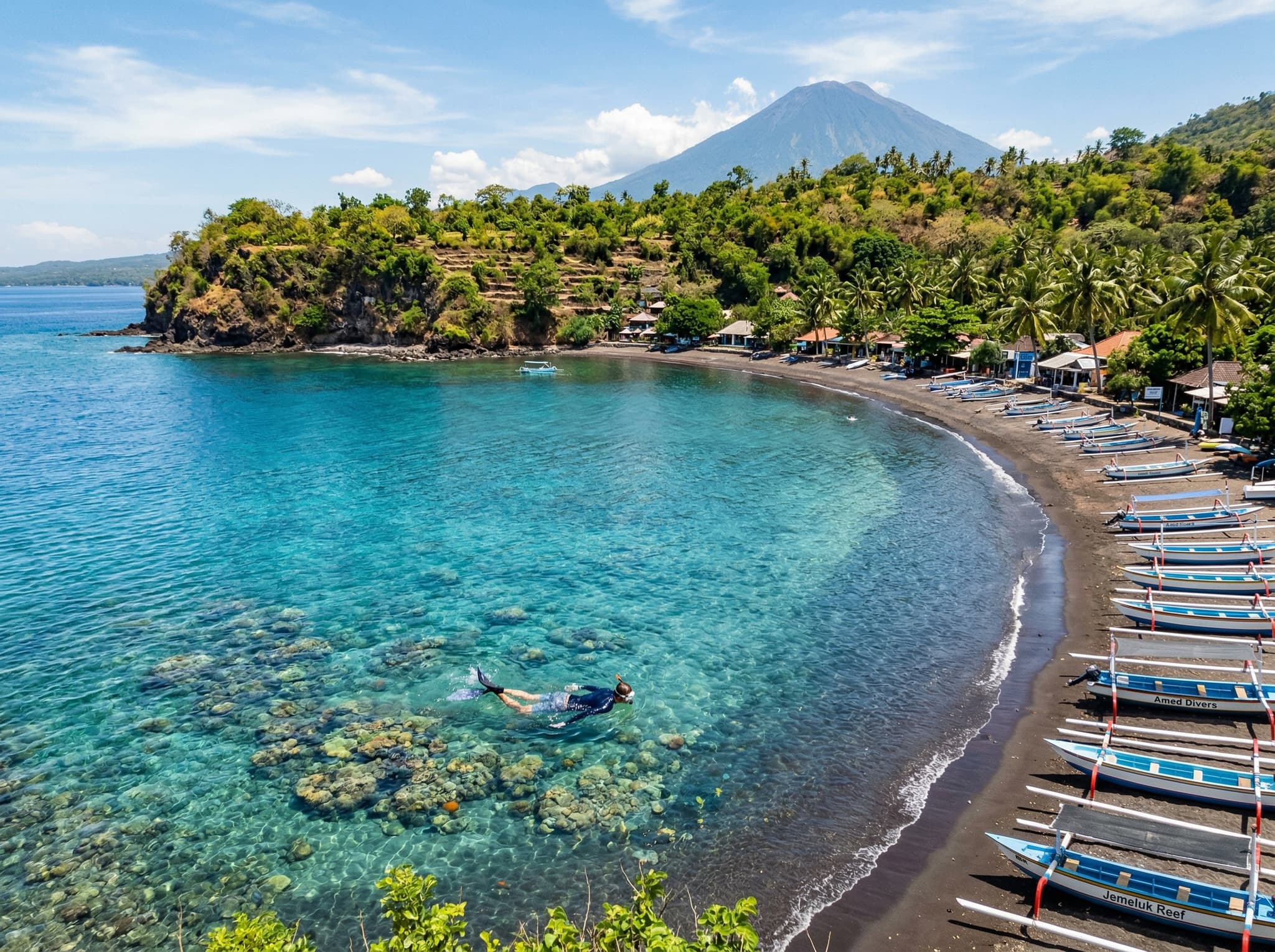 Jemeluk Bay, Amed — a sheltered crescent-shaped bay with clear turquoise water over coral, the entry point for shore snorkeling described in the article as accessible within thirty meters of the beach.