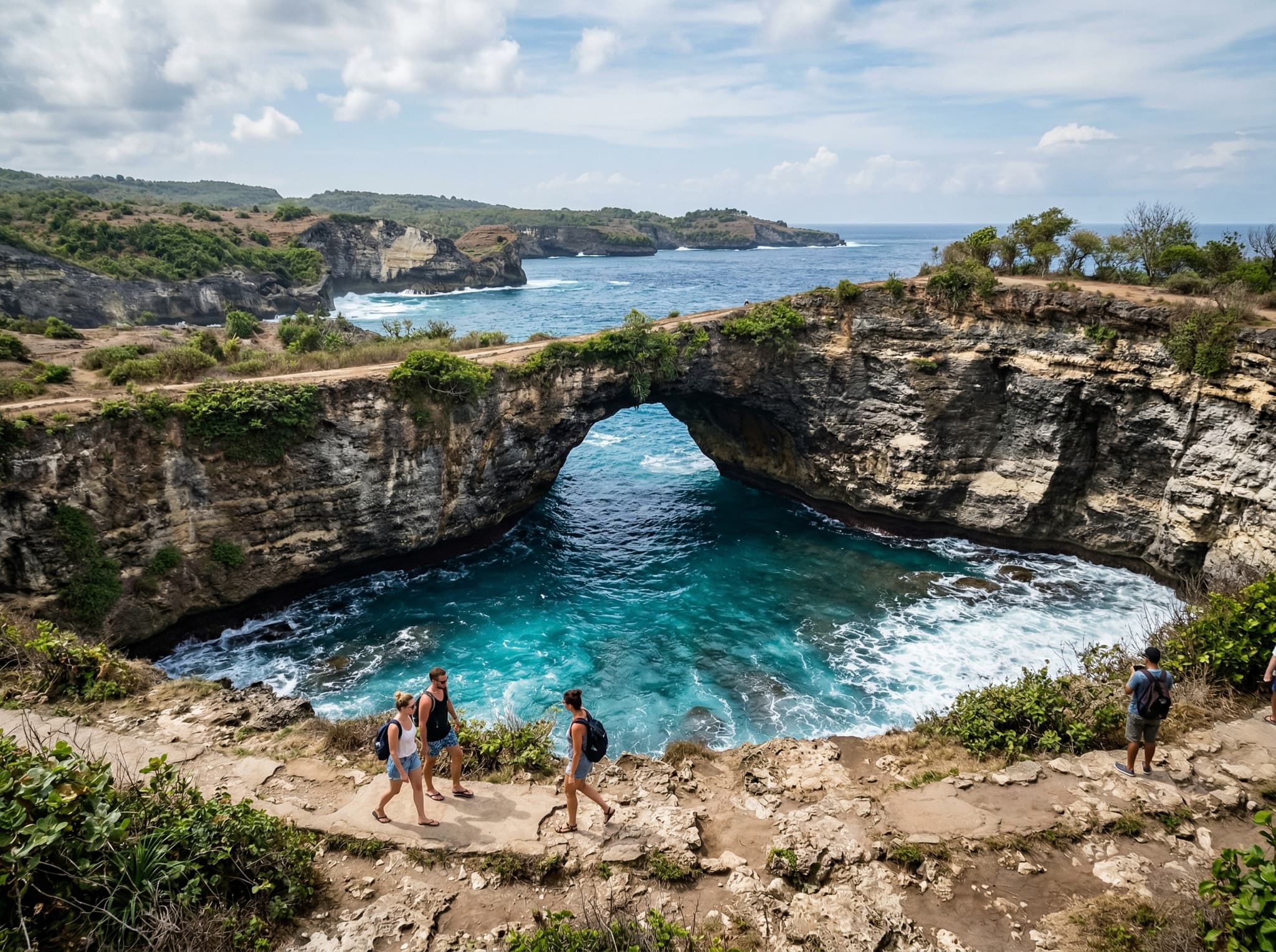 Broken Beach natural rock arch on Nusa Penida — the dramatic clifftop viewpoint over the circular cove, showing the arch formation and turquoise water below, illustrating the nearby companion site the article recommends pairing with Angel's Billabong