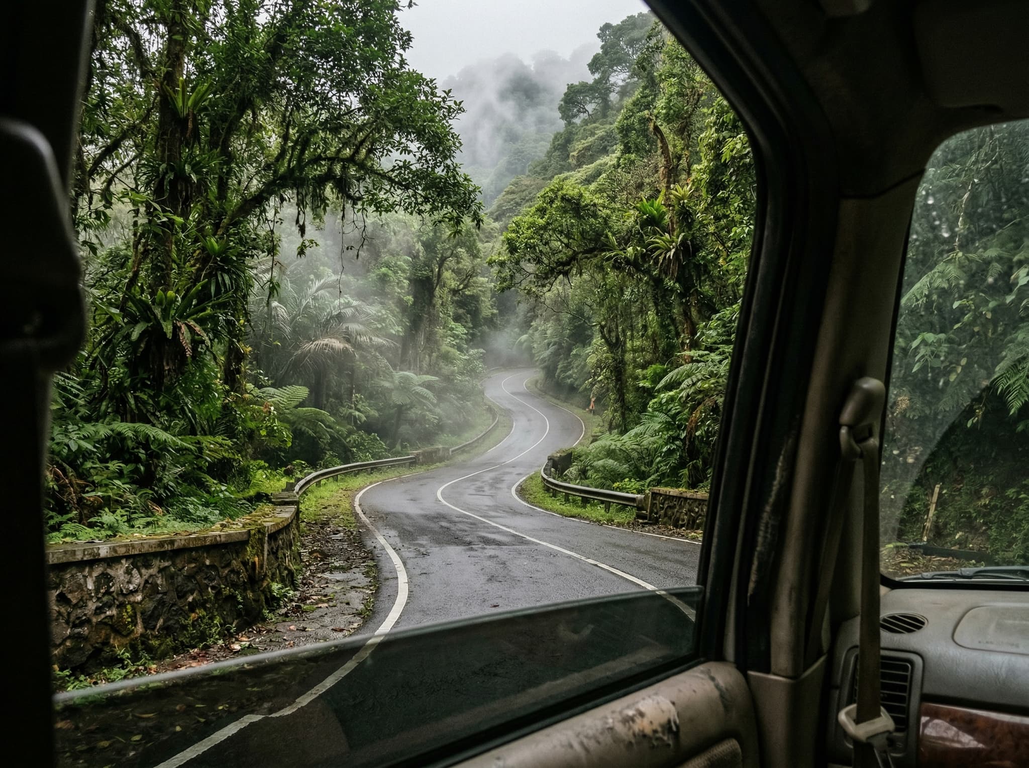 The winding mountain road between Bedugul and Munduk in Bali, showing the steep, narrow asphalt road cutting through dense tropical forest — illustrating the rewarding but demanding drive that keeps Munduk uncrowded and accessible mainly to committed travelers