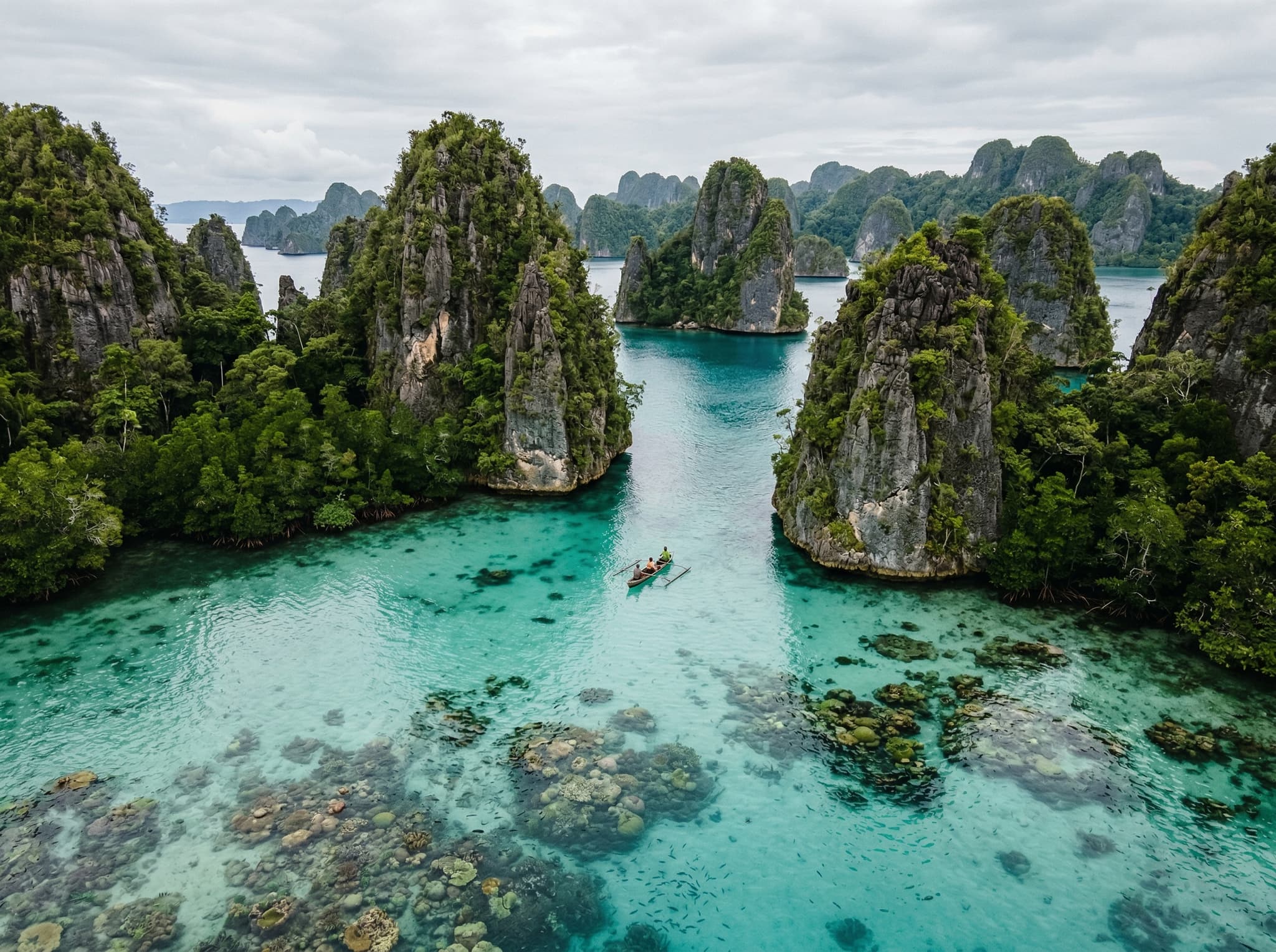 Kabui Bay in Raja Ampat showing dramatic vertical limestone karst formations rising from the sea surface with coral-rich water below — capturing the article's description of scenery above and below the waterline being equally spectacular at this intermediate snorkeling site