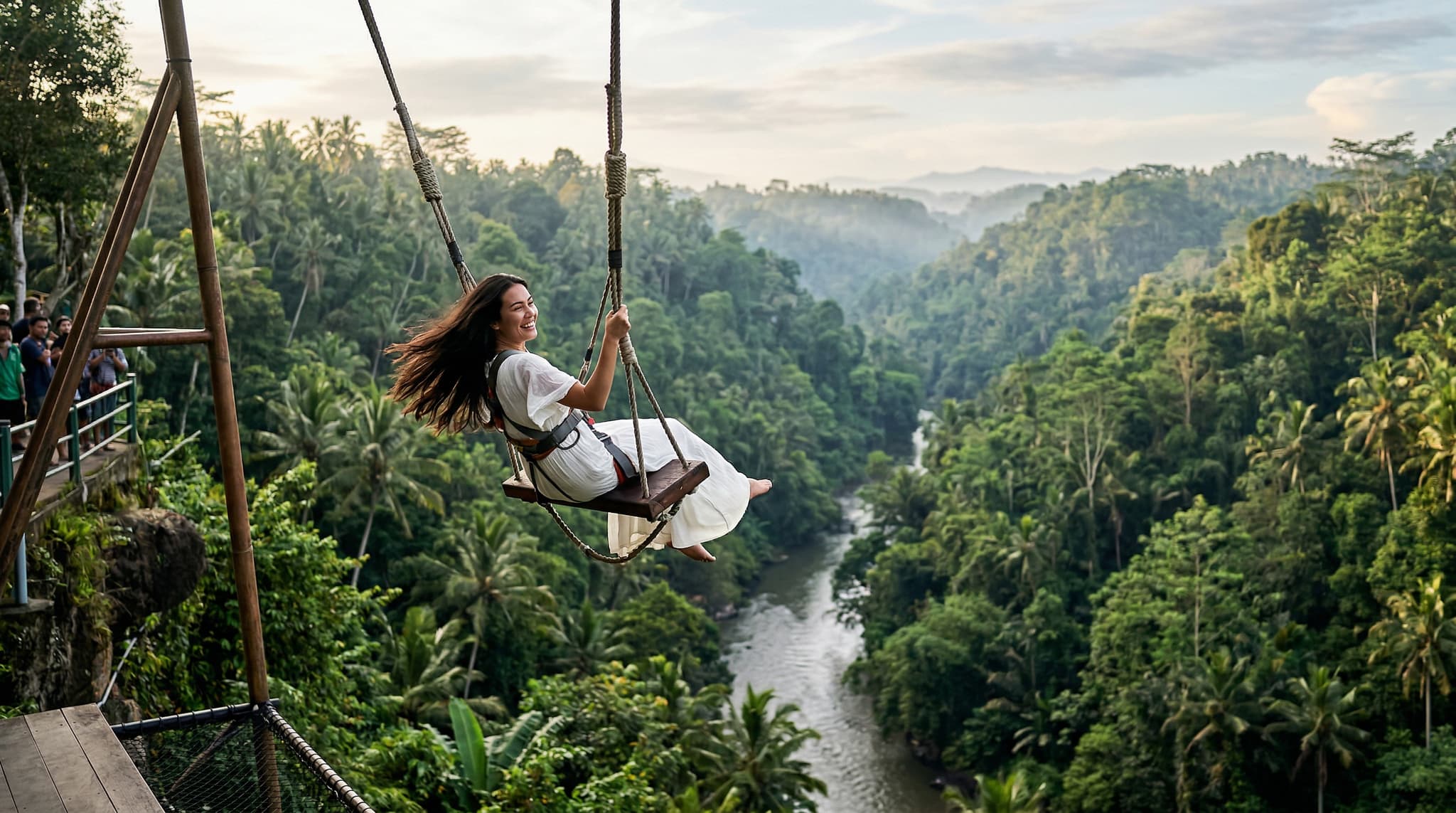 A person mid-swing on the Bali Swing, suspended over a lush jungle river valley in Bongkasa Pertiwi, with dense tropical canopy below and soft morning light — illustrating the dramatic aerial experience at the center of this article's honest assessment.