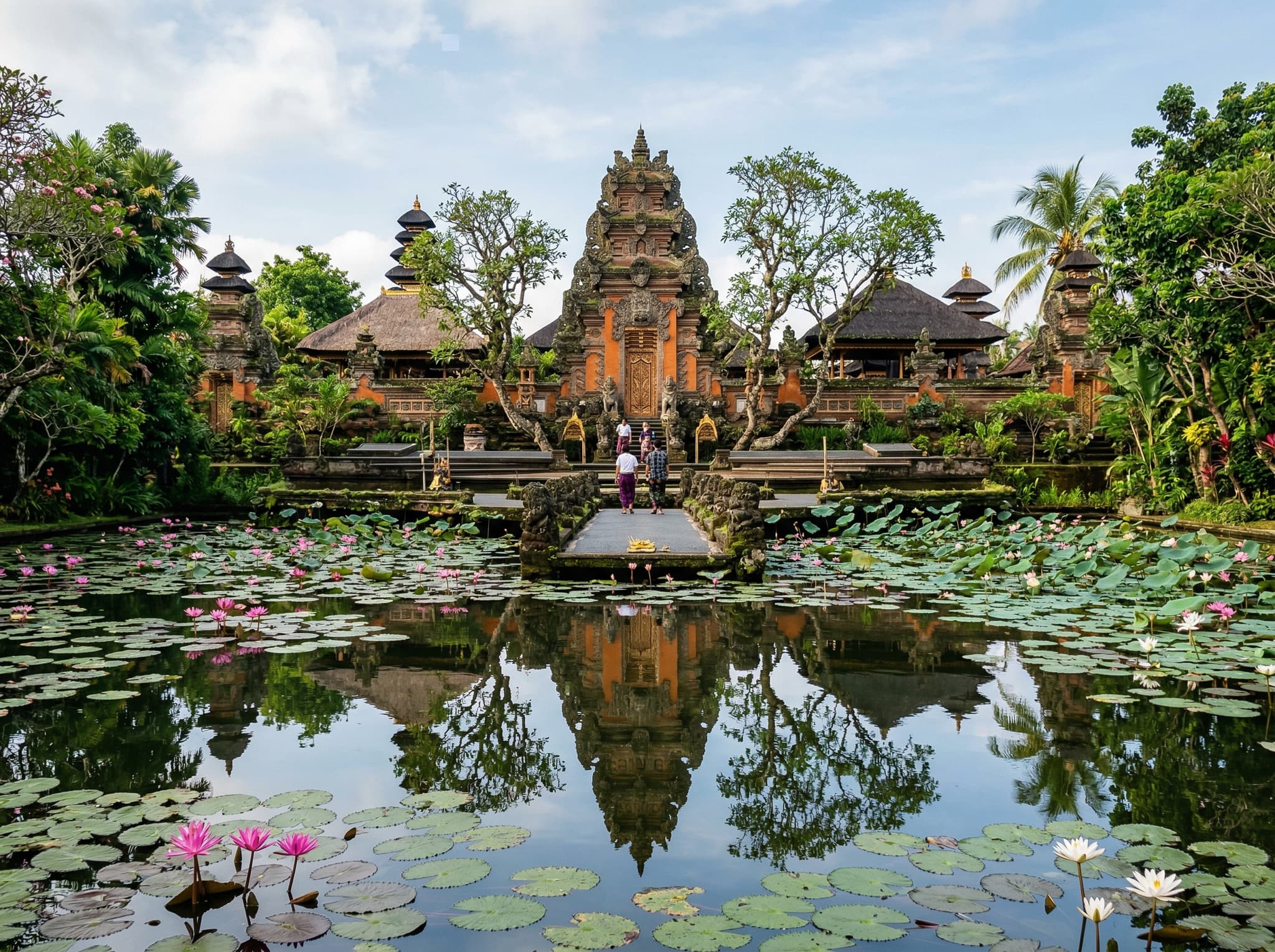 Pura Taman Saraswati temple in Ubud, Bali — the lotus pond and ornate Balinese temple gate reflected in still water, illustrating the article's suggestion to pair a market visit with this two-minute walk away spiritual landmark