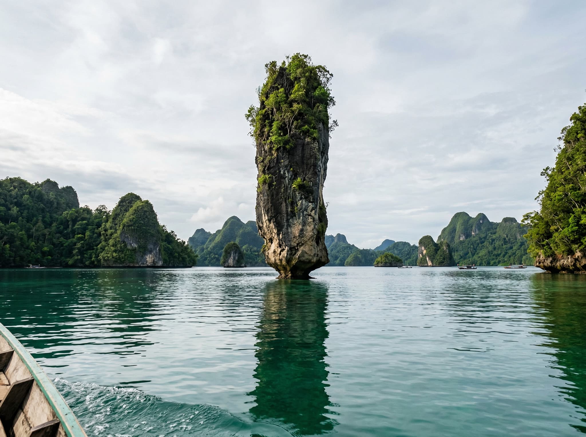 Batu Pensil (Pencil Rock), the narrow limestone pillar balanced on a thin base near the entrance of Kabui Bay, Raja Ampat — one of the bay's two unofficial landmark formations that signal arrival in the bay proper