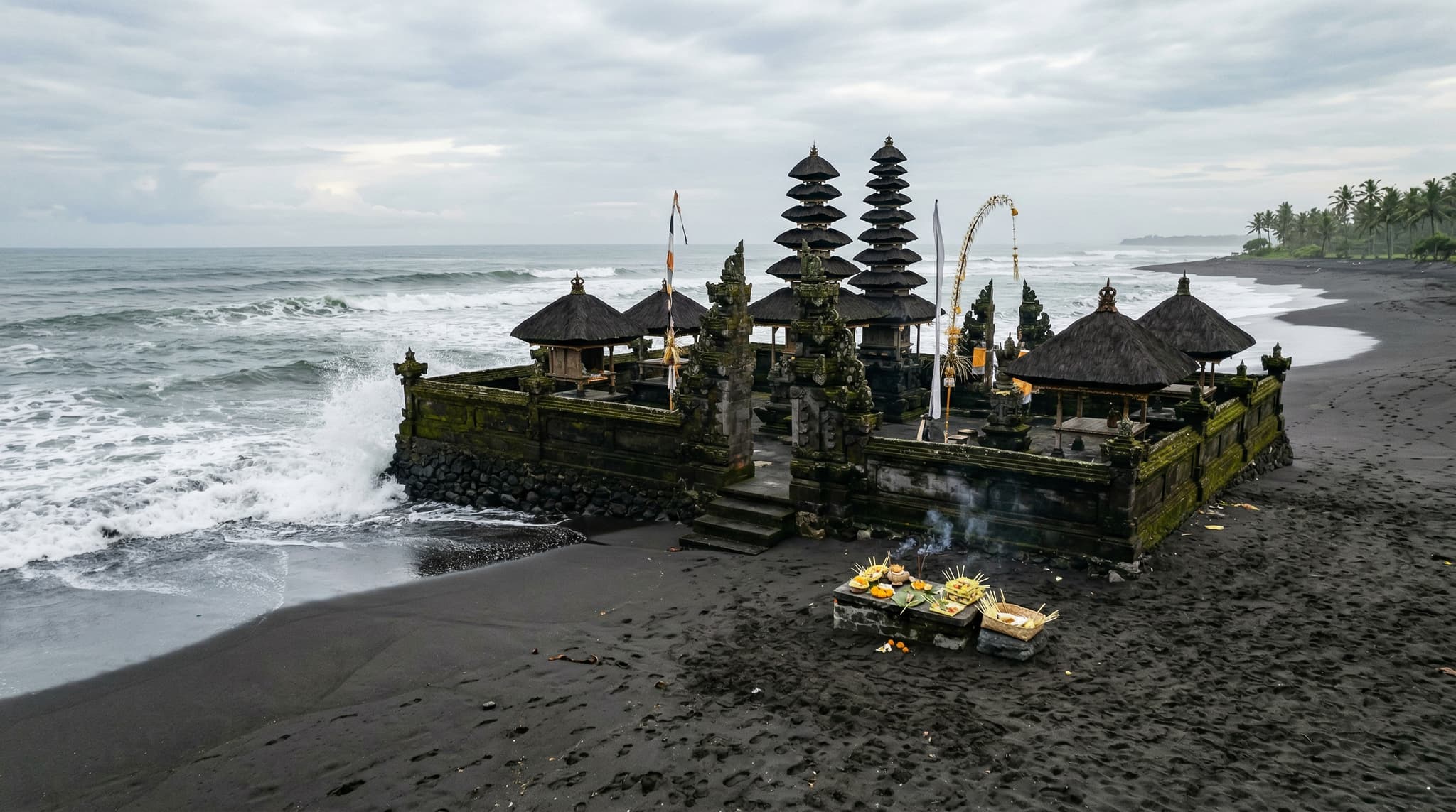 Pura Masceti sea temple on Masceti Beach in Gianyar, Bali — stone shrines and split gates against a black volcanic sand shoreline with the Indian Ocean in the background, conveying the temple's elemental, uncrowded character
