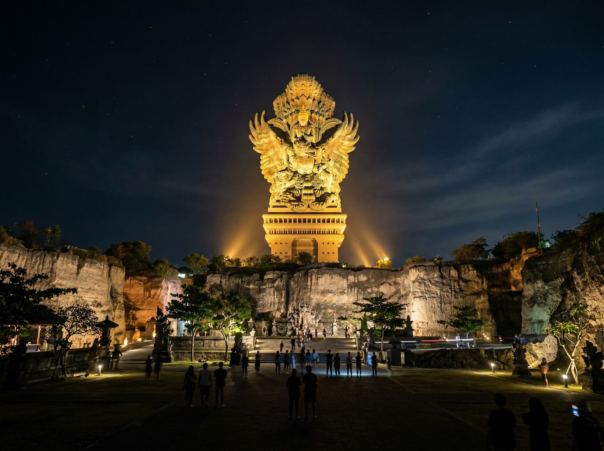The GWK Cultural Park at night with the Garuda Wisnu Kencana statue illuminated against the dark sky — representing the article's closing recommendation to stay after dark when the statue is lit and the limestone glows faintly, the version of GWK the writer calls worth your time