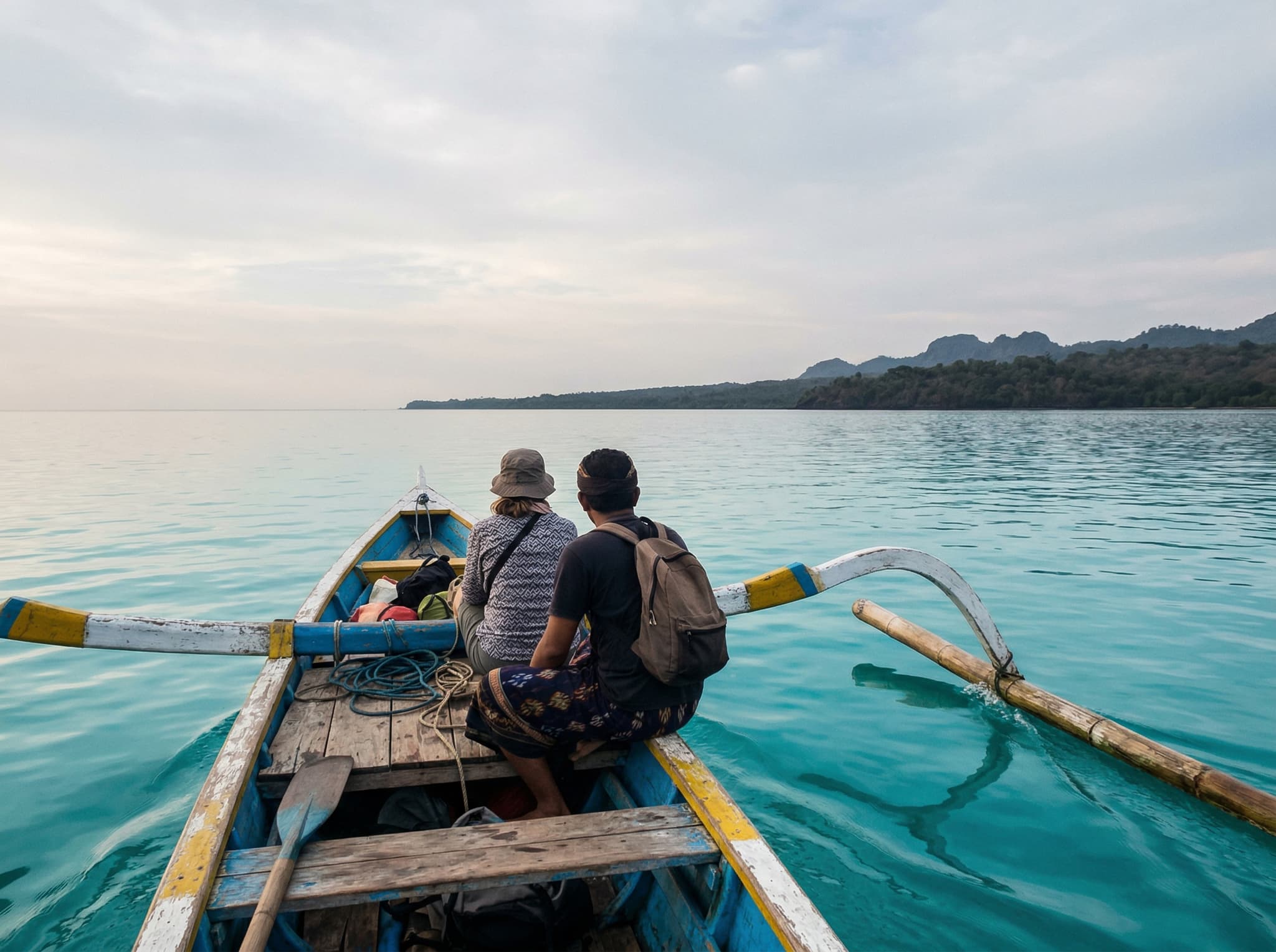The boat crossing from Labuan Lalang jetty to Menjangan Island — a small wooden boat on flat calm water with the island's forested silhouette ahead, capturing the 30-minute journey described in the article