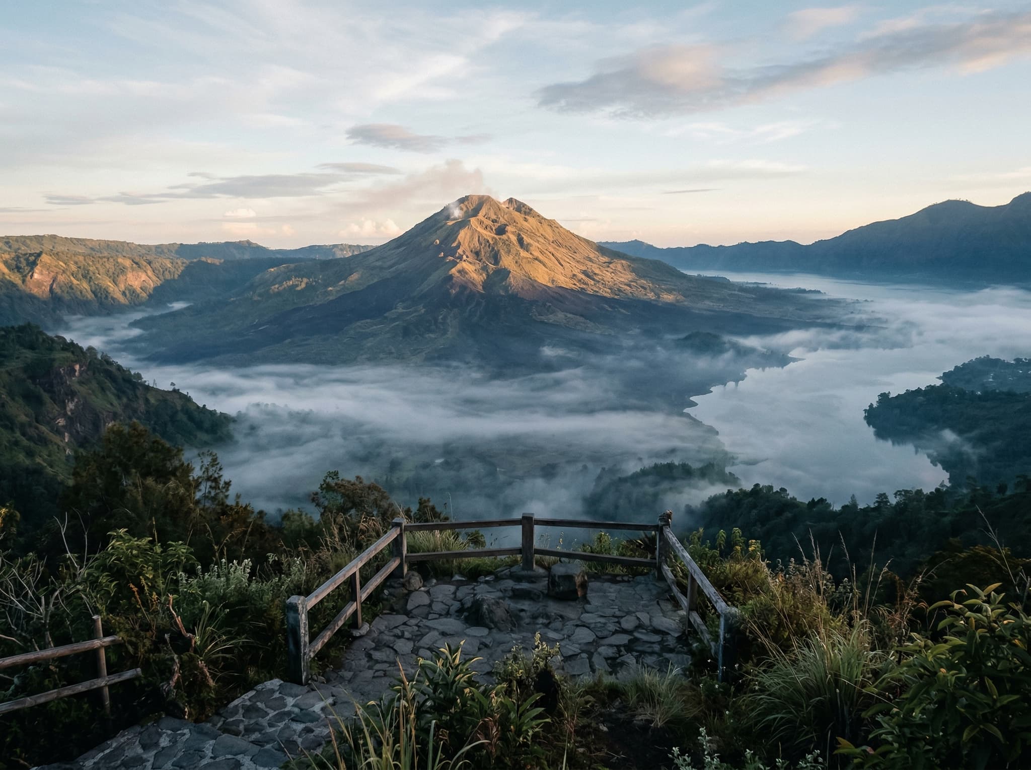 Early morning light on the Kintamani caldera with mist still in the valley and the volcano catching the first sun — evoking the overnight stay experience described in the article's closing section about the rewards of lingering in the highlands