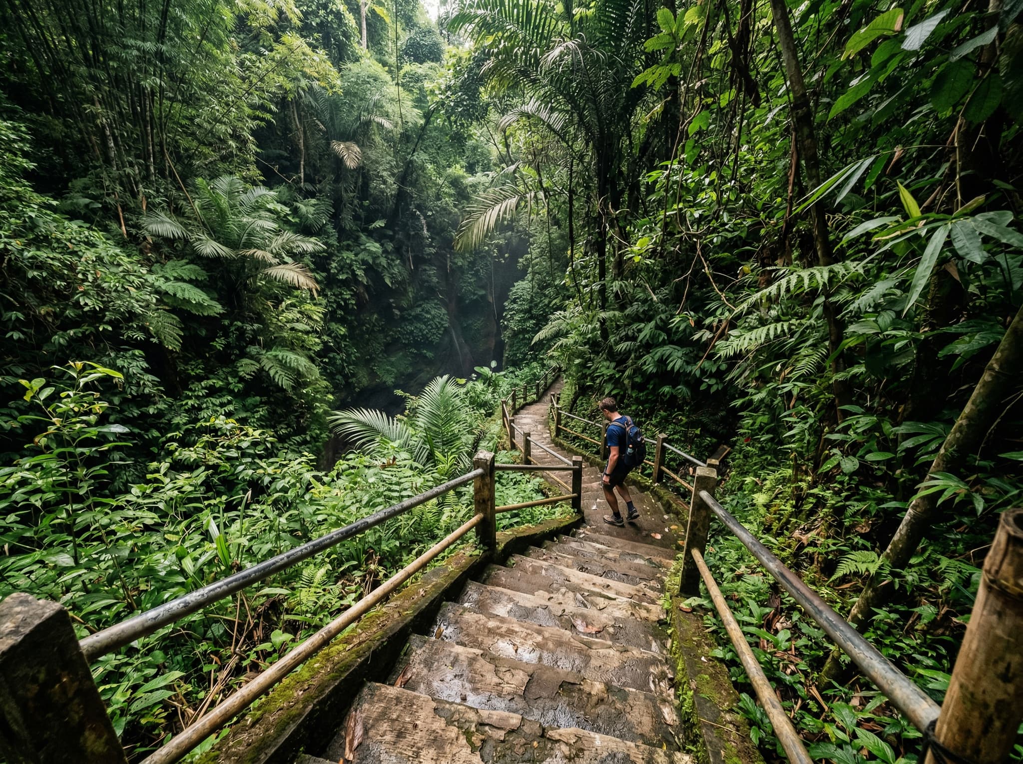 Steep concrete stairs descending into a jungle ravine on the trail to Melanting Waterfall, Munduk, Bali — visually conveying the 350–500 step descent that the article warns is the most physically demanding part of the hike