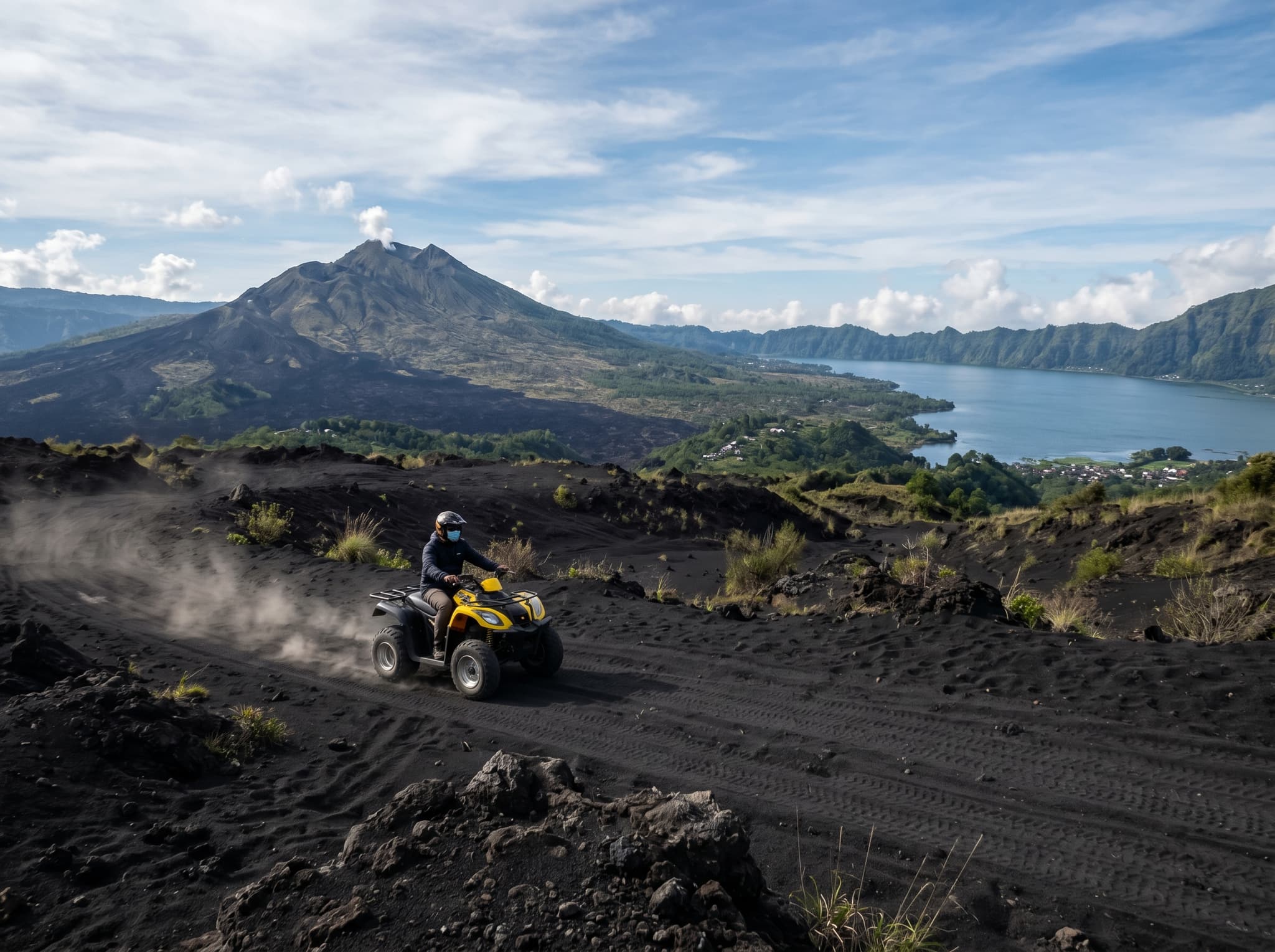The volcanic black-sand terrain near Kintamani, Bali, with Mount Batur and Lake Batur visible in the background — showing the dramatically different landscape offered by Kintamani ATV operators compared to the jungle and rice paddy routes near Ubud