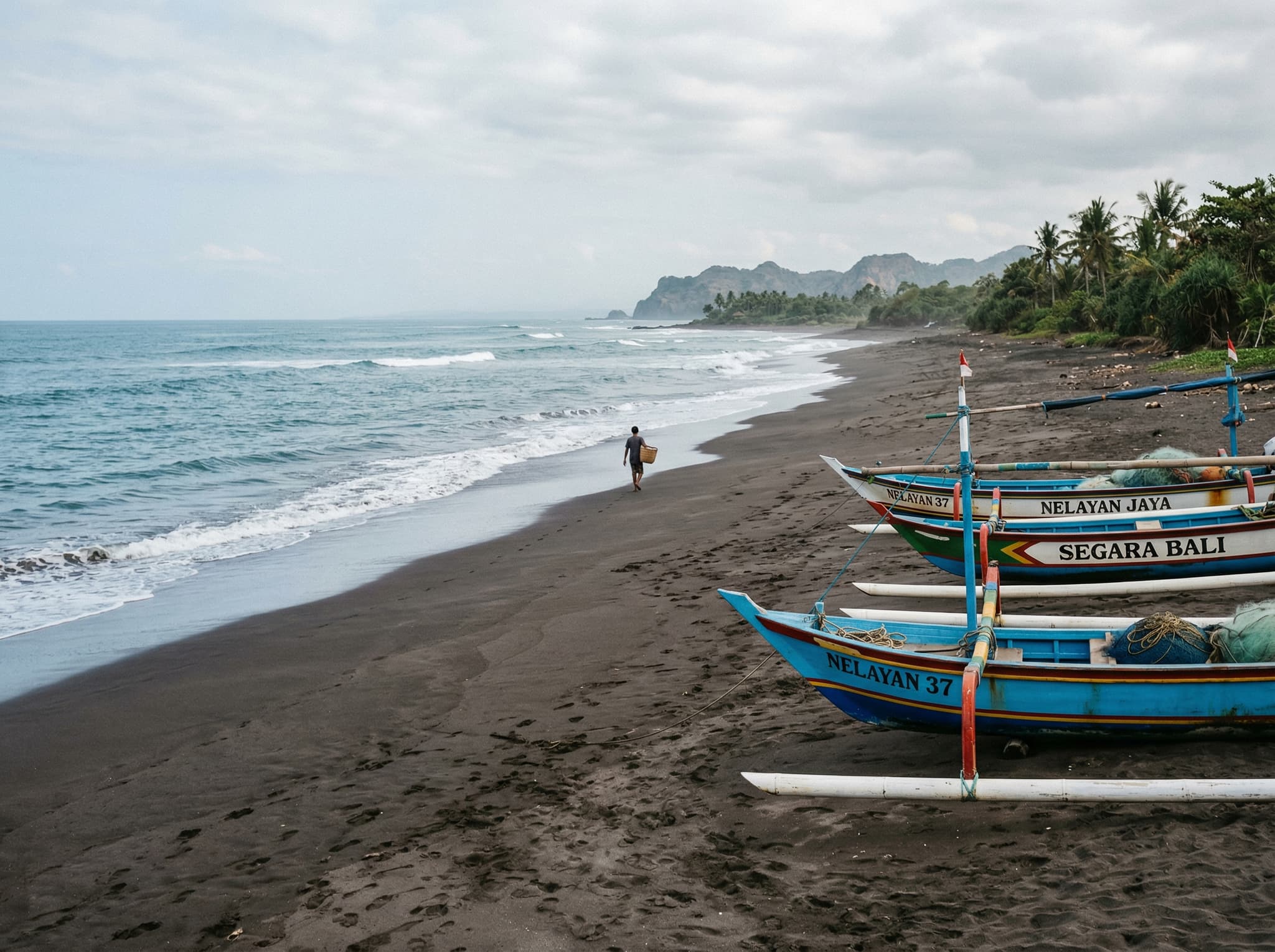Nelayan Beach, the quiet pocket beach tucked between Batu Bolong and Berawa in Canggu — nearly empty dark sand shoreline with fishing boats, showing the contrast with the crowded main beach just minutes away that most visitors walk right past