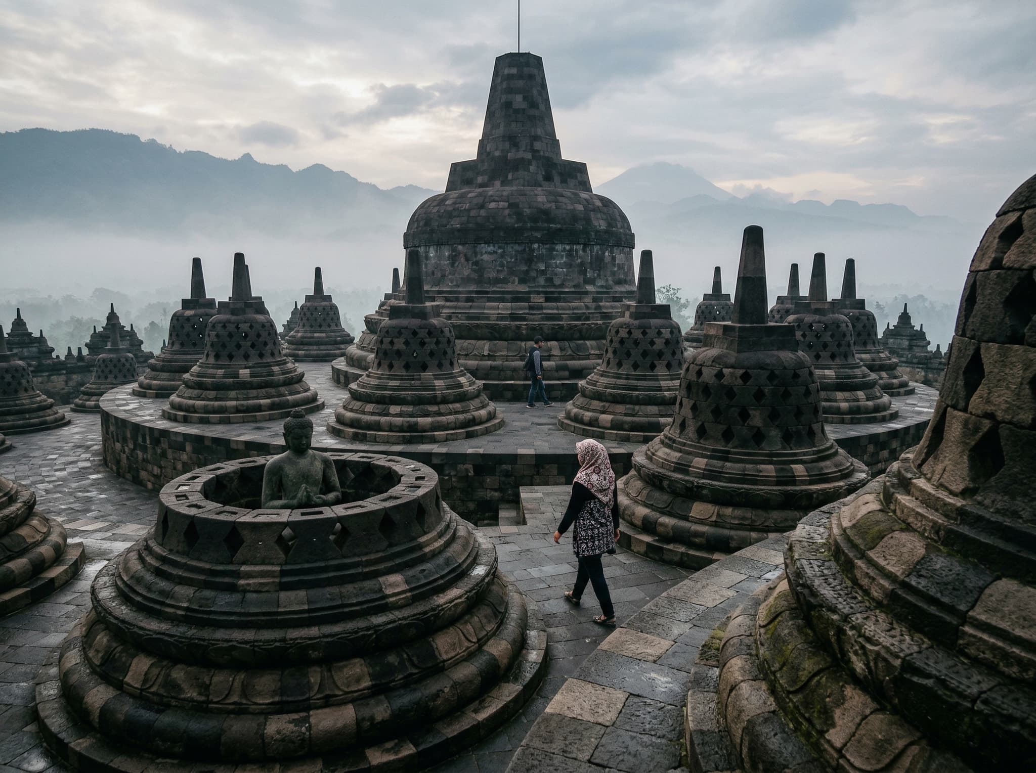 Ground-level view of Borobudur Temple's upper terraces showing the iconic bell-shaped stupas and central spire at close range, representing the VIP sunrise temple experience that Dagi Hill offers as a panoramic alternative — contextualizing the cost comparison discussed in the article's opening section